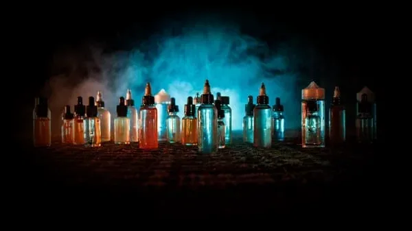 Rows of e-liquid bottles in blue smoke