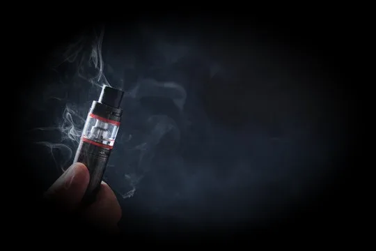 Hand holding a vape with smoke